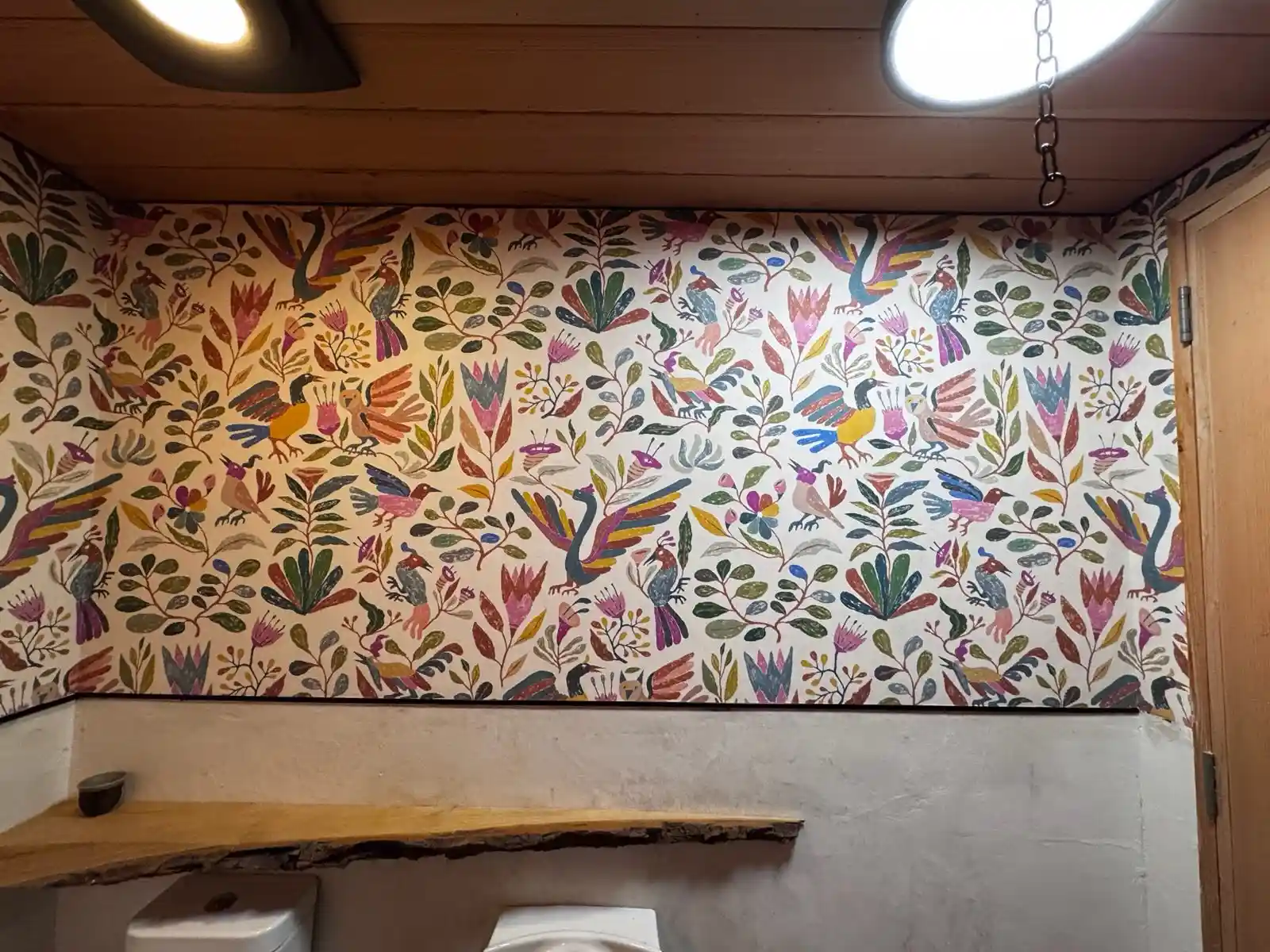 A room with botanical-patterned wallcovering and a light upholstered sofa