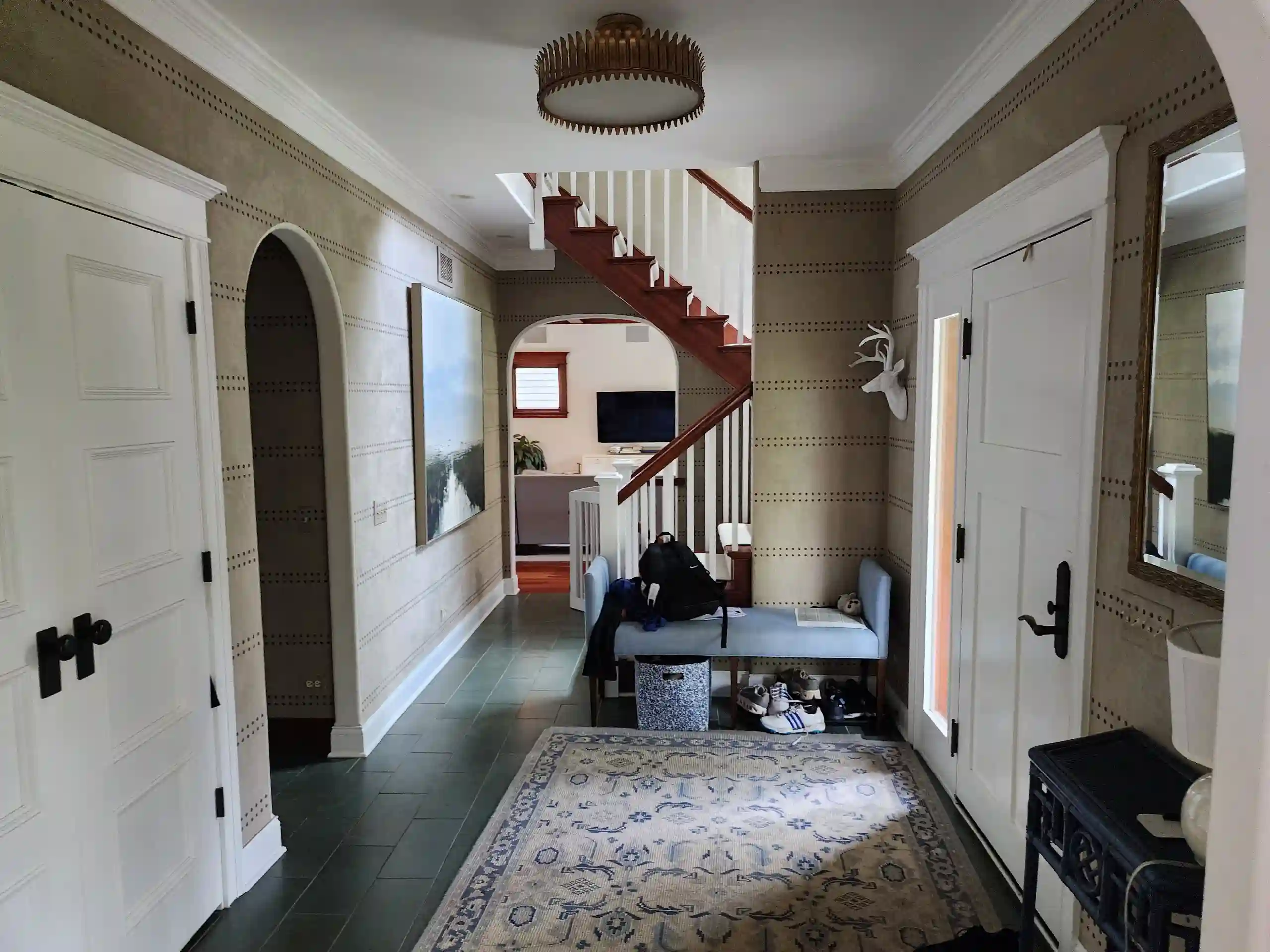 A light-filled interior hallway with a staircase and wide doorway