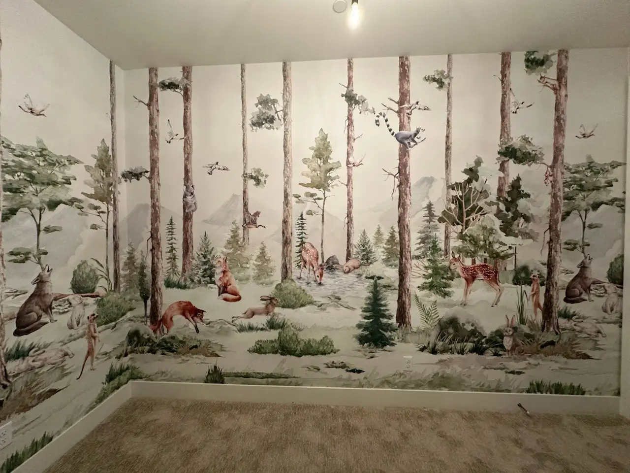 A woodland mural with trees and small animals covering a room wall